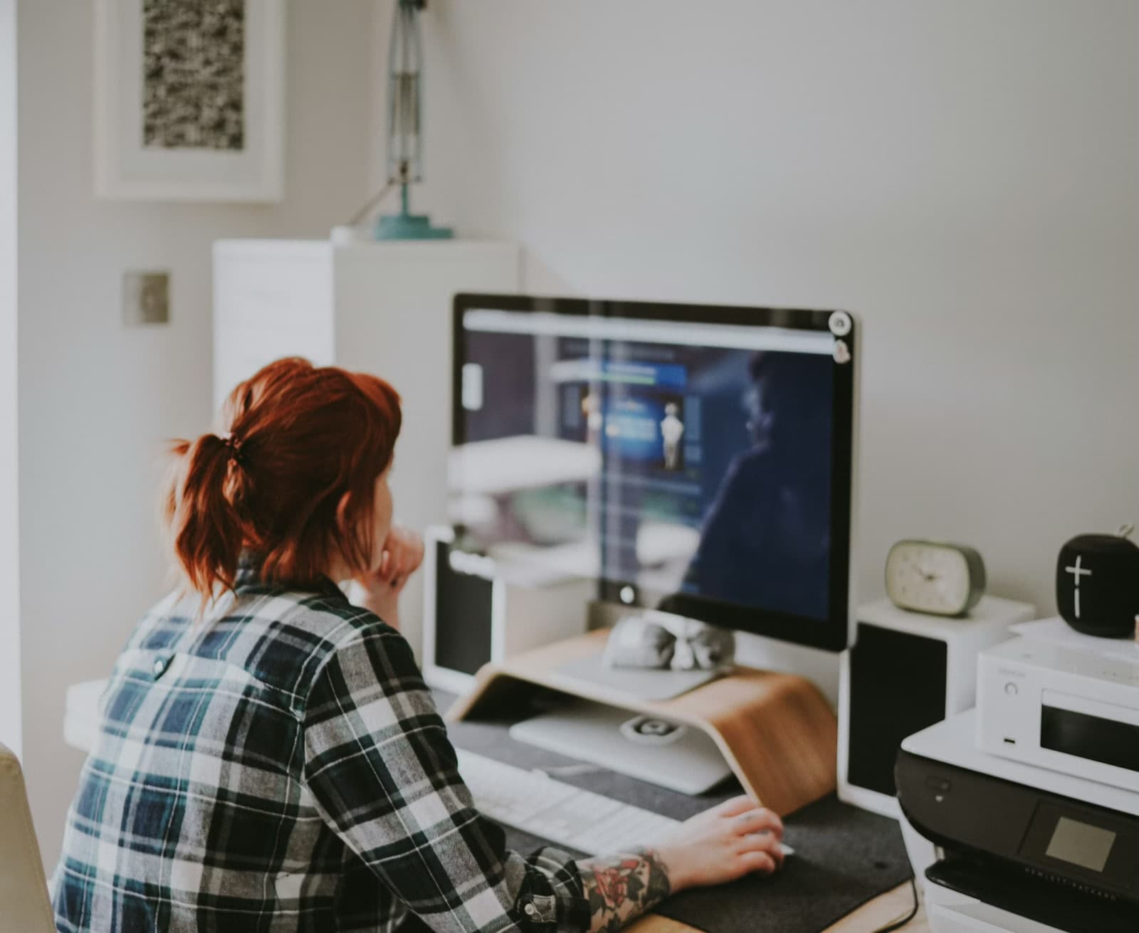 A remote attendee at a home desk watching a live stream play on a desktop monitor